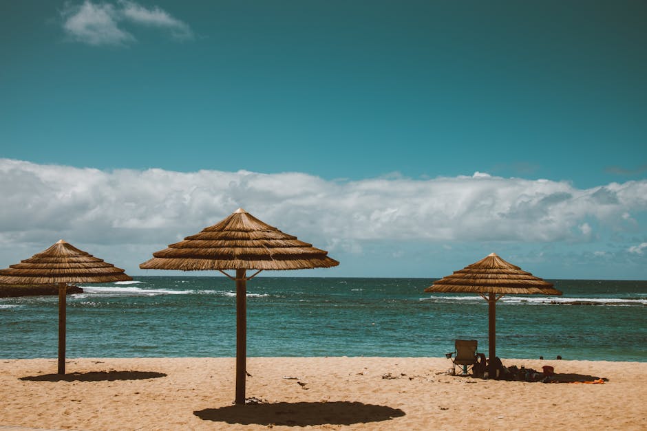 A person relaxing under an umbrella on a serene Hawaiian beach, embodying vacation and peace of mind for travelers